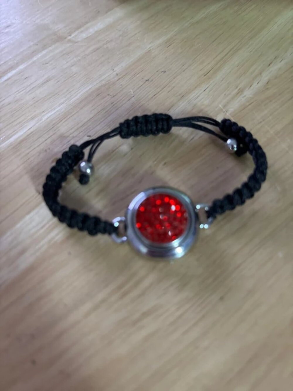 Red textured stone in silver tone bezel black cord bracelet